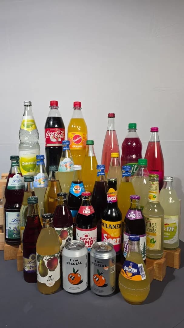 Verschiedene Flaschen mit Erfrischungsgetränken auf einem Tisch angeordnet.