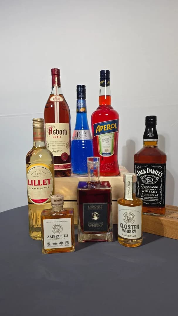 Verschiedene Spirituosenflaschen auf einem Tisch, darunter Whiskey, Likör und Schnaps.