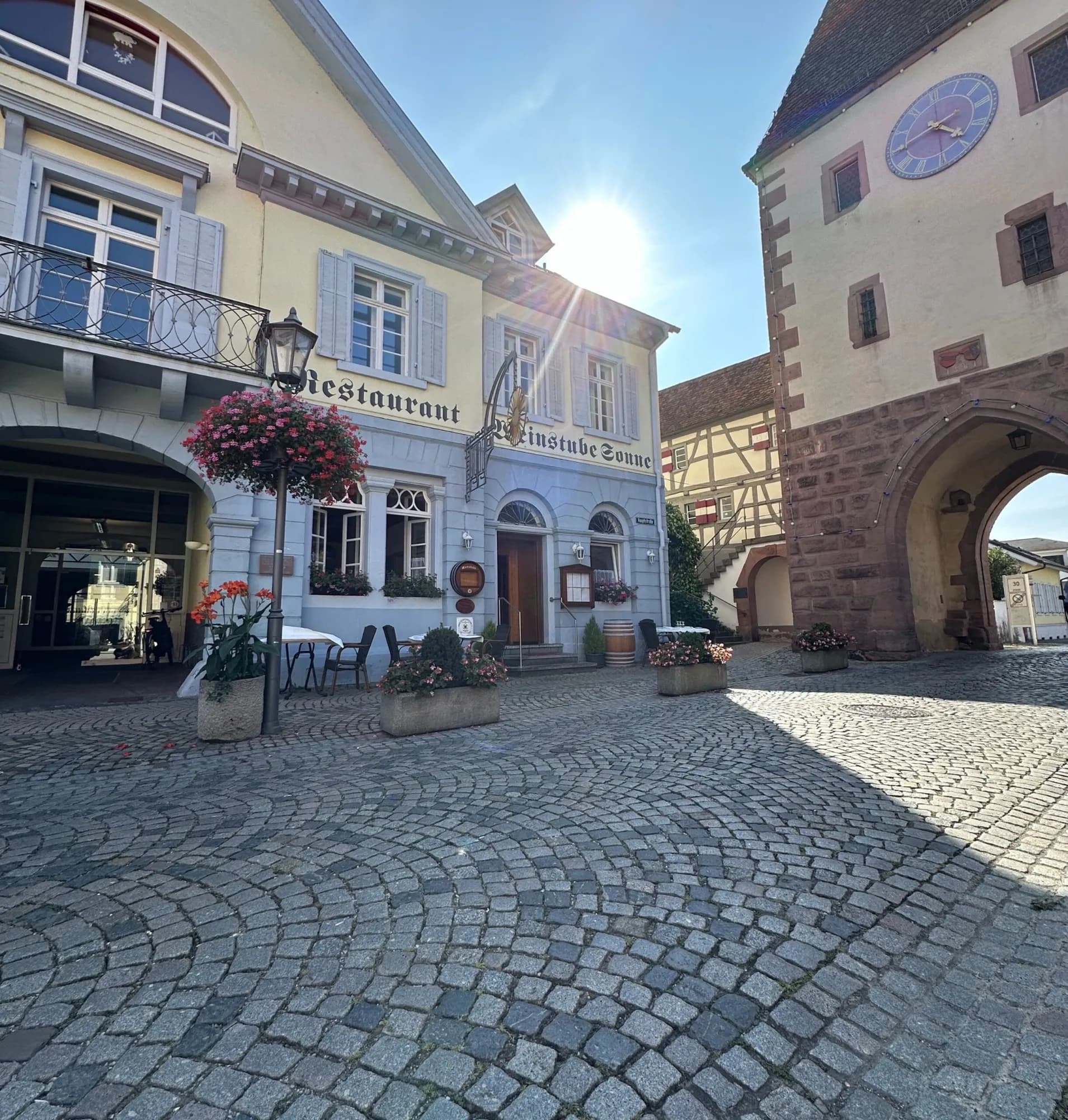 Blick auf eine historische Stadtanlage mit Pflastersteinen und Blumenverschönerung.