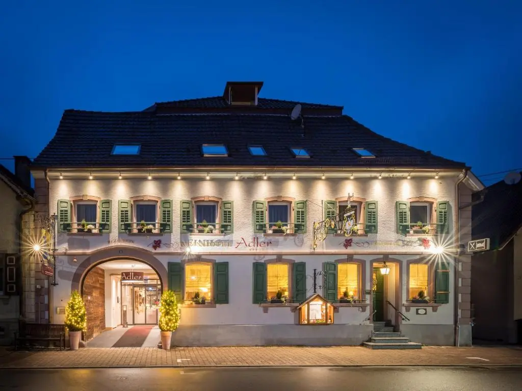 Historisches Gebäude mit grünen Fensterläden und warm erleuchteten Fenstern bei Nacht.